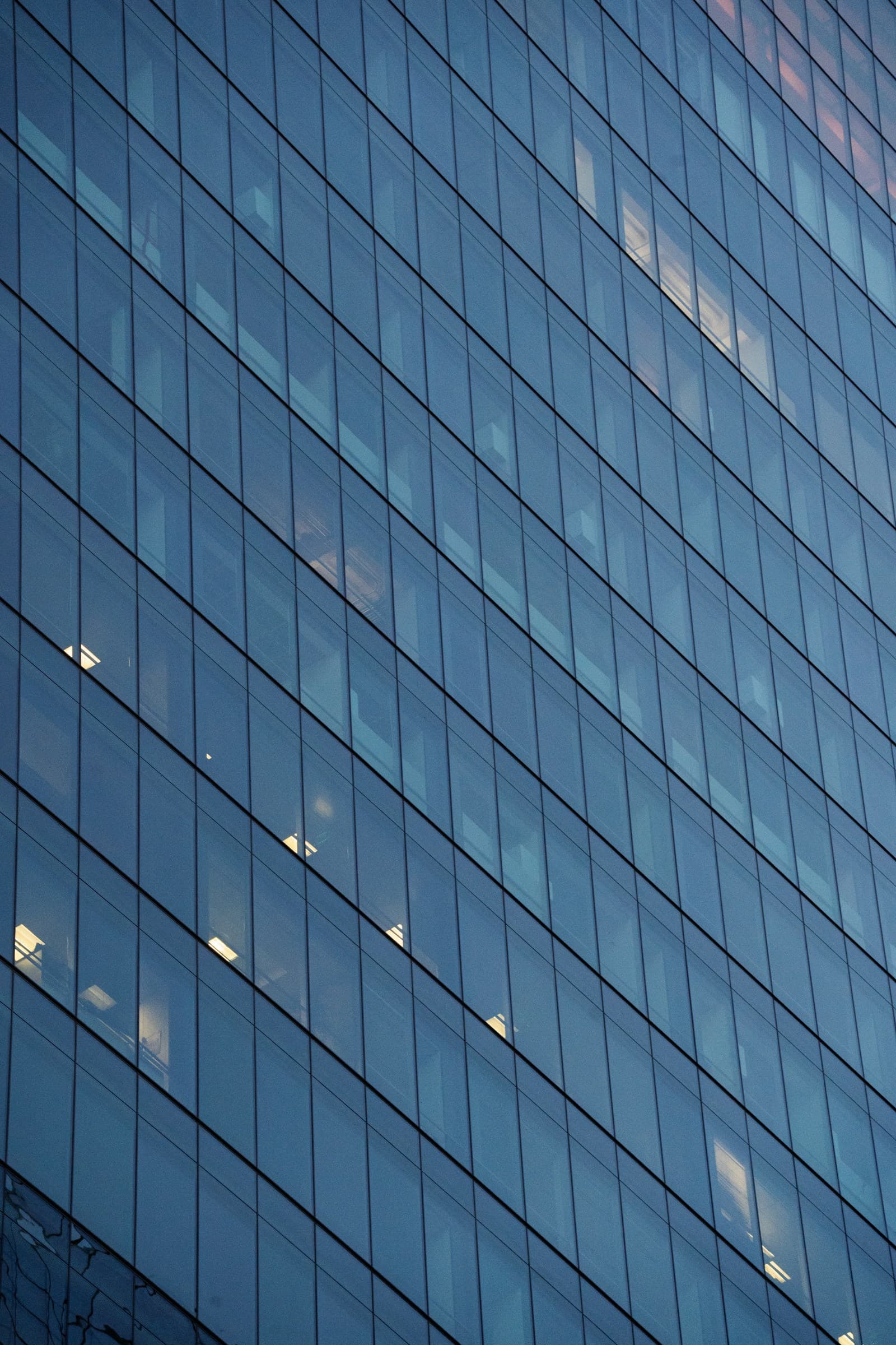 Fachada de vidrio de un edificio moderno, grilla geométrica de ventanas al atardecer